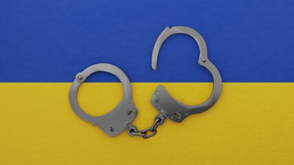 A half opened steel handcuff in center on top of the national flag of Ukraine