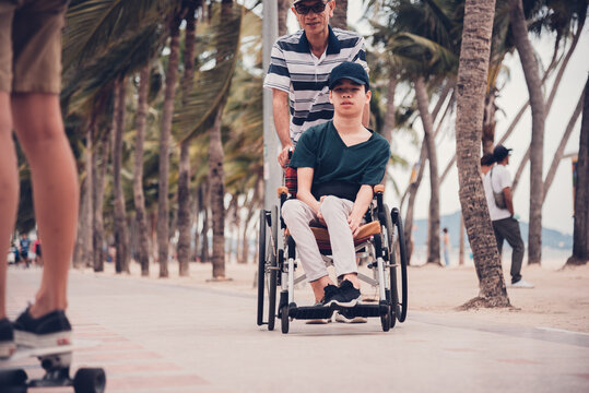 Disabled child smile face with activity outdoor on the street in front of the beach, Lifestyle of disability kid travel holidays with family, Happy teenger on wheelchair.