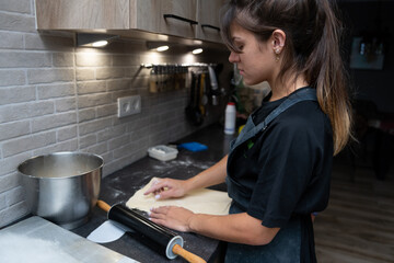 photograph of a young girl kneading a homemade dough at home