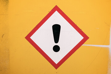 Photograph of a generic real diamond warning label against a bright yellow wall.