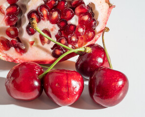 Ripe pomegranate and cherry on a white background.
