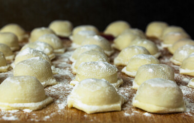 Raw dumplings with meat on a board sprinkled with flour