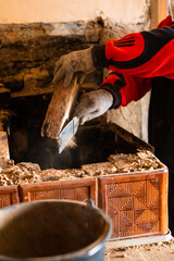 Man destroys an old brick stove, black brick in soot, dismantling the old kitchen surface.