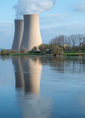 Fototapeta premium Nuclear power plant against sky by the river at sunset
