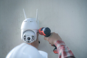 Technician installing IP  wireless CCTV camera installing security equipment water proof cover to...