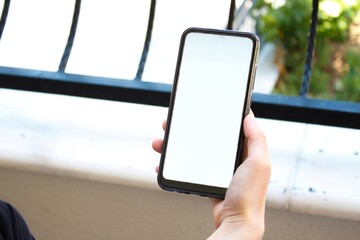 Female hand holding black smartphone, blank white screen for mockup.