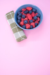 bowl full of fresh berries on a pink background