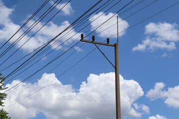 Fototapeta premium Electricity high voltage system, electric pole, transmission line, insulator supporting, isolated on blue sky and white cloud background closeup.