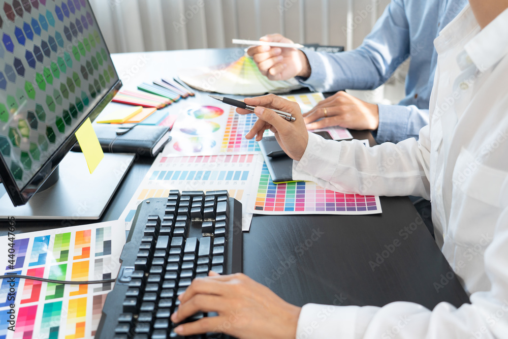 Poster graphic designer or creative working together coloring using graphics tablet and a stylus at desk wi