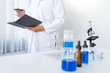 Scientist wear lab coat and protective wear are working with research or doing investigations with test tubes in experiment, Laboratory and development concept