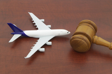 Wooden judge gavel and airplane model on wooden background.
