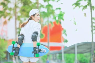 Asian women surf skate or skates board outdoors on beautiful summer day.Fashion portrait of female hands holding surf skateboard.