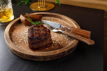 filet mignon medium rare served on a wooden plate with baked potatoes
