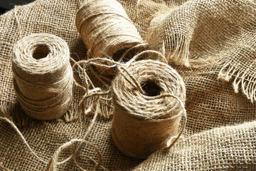 An image of three spools of burlap thread on weaved burlap fabric. 