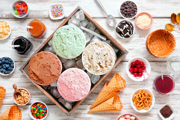 Summer ice cream buffet with a variety of ice cream flavors and sweet toppings. Overhead view table...