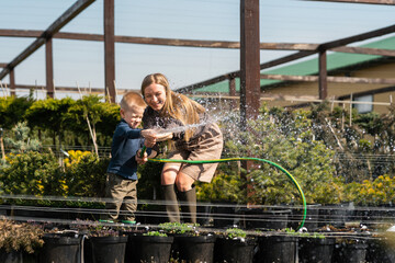 Woman with her son watering the pots of plants with a hose