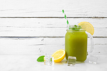 Iced matcha lemonade in a mason jar glass with paper straw against a white wood background - obrazy, fototapety, plakaty