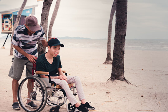 Disabled child smile face with activity outdoor on the street in front of the beach, Lifestyle of disability kid travel holidays with family, Happy teenger on wheelchair.