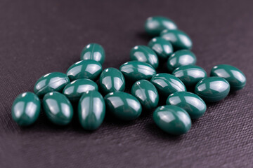 
Green pills on a black background.
Close-up.