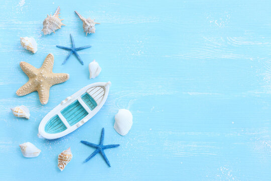 nautical concept with white decorative sail boat, seashells over blue wooden background