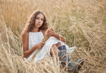 Naklejka na ściany i meble Teen girl in wheat field in a summer day
