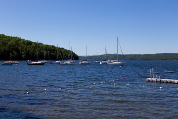 Fototapeta na wymiar Sailboats moored on fresh water glacial Lake Memphremagog seen during a sunny summer morning, Georgeville, Eastern Townships, Quebec, Canada