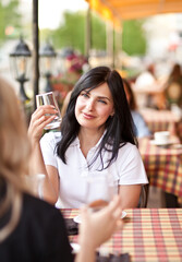 Smiling young woman at cafe drinking beverage. Communication and friendship concept.