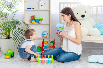 mom teaches the child at home by playing educational toys in the children's room. A happy, loving family.