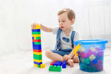 a child with a constructor at home, a cute boy plays or collects a colored constructor
