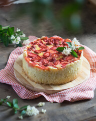 Baked strawberry pie cake tart with flowers on red napkin on rustic wooden table. Selective focus