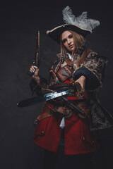 Elegant woman pirate with tricorn holding gun and saber