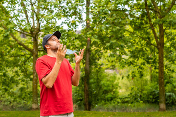 Fototapeta premium A young man in a red t-shirt removing his surgical mask at the end of the coronavirus pandemic. End of restrictions abroad, happy to be able to breathe well again, covid19, yellow background