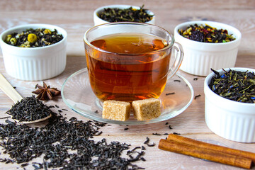 Tea assortment. Various kinds of tea in bowl. Prepared tea in a cup with sugar.