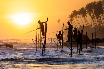 Stilt fishermen in silhouette sunset on the Koggala beach, Sri Lanka.