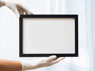 A woman wearing medical gloves holds an empty frame. Here can be your text