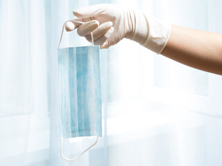 A woman's gloved hand holds a medical mask. Protection against infection.