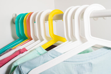 A lot of colorful hangers on a rod, on a white background of the wardrobe. Store concept, sale, design, empty hanger.