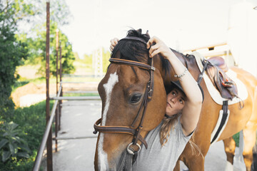 Equestrian sporty female putting bridle on horse