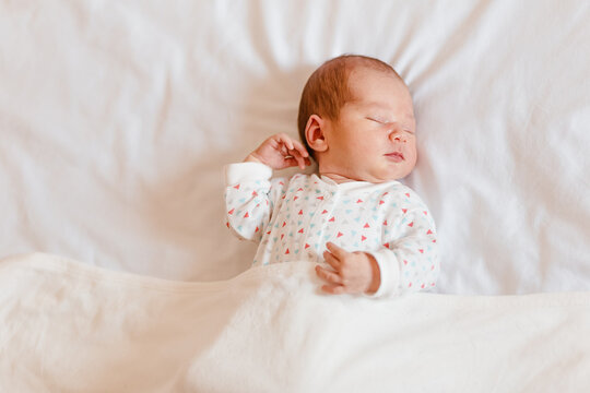 Newborn baby sleeps sweetly on white plaid. Newborn photo shoot