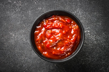Tomato sauce in a bowl at black stone table. Top view image.