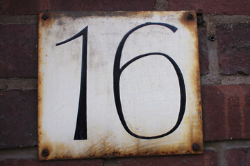 House number "16" attached to a brick wall