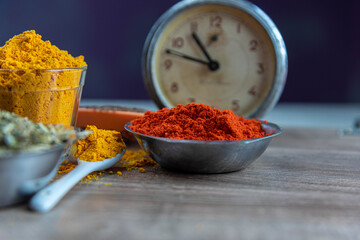 Colorful culinary spices and clock on wooden surface