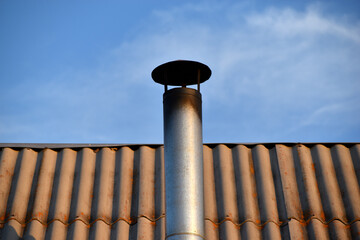 Iron chimney on the roof of the house