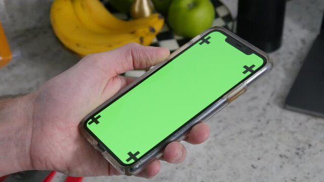 Man holds up iPhone green screen