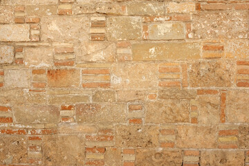 The brick wall of the old building in the background. A wall made of shell. Sandstone building blocks. Rough texture of a brick wall made of sand and shells