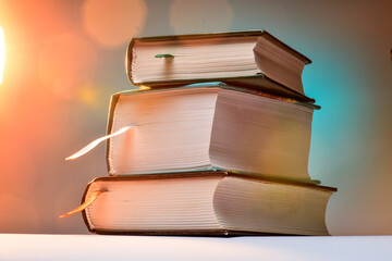 Three thick books on an abstract background with blurred lights.