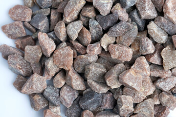 Red quartzite crumb on a white background top view. Decorative stone chips for landscaping. Crushed stone close-up.