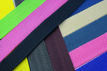 Colored background from belts folded diagonally. Colored polyester belts, sample palette for making shoulder straps for bags and backpacks.