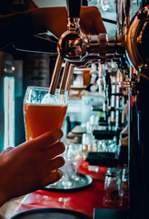bartender hand at beer tap pouring a draught beer in glass serving in a bar or pub