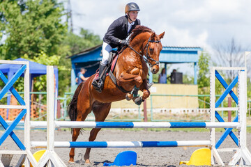 Young rider man jumping over the barrier